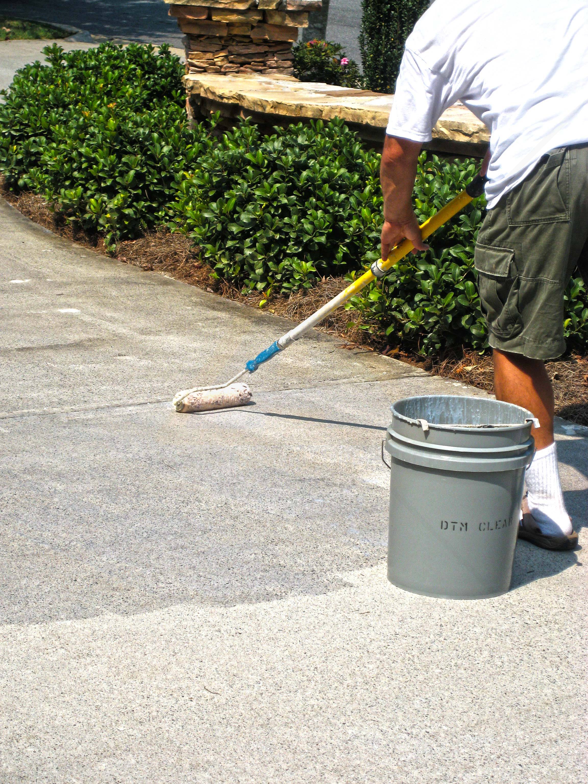 Clear sealer being professionally applied to a concrete driveway